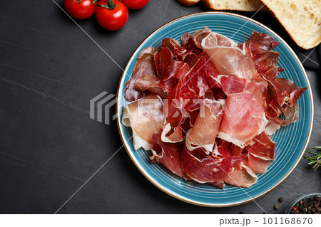 Tasty prosciutto served on black table, flat lay Tasty prosciutto served on black table, flat lay 101168670