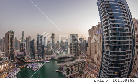 Aerial view to Dubai marina skyscrapers around canal with floating boats day to night timelapse Aerial view to Dubai marina skyscrapers around canal with floating boats day to night timelapse 101169265
