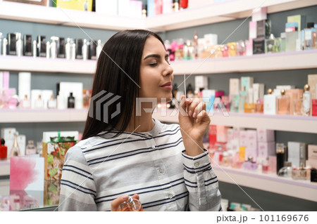Beautiful young woman choosing perfume in shop Beautiful young woman choosing perfume in shop 101169676