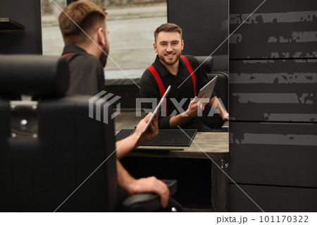 Young business owner with tablet in barber shop 101170322