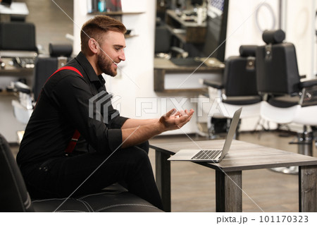 Young business owner working with laptop in barber shop 101170323