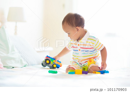 Baby boy playing on bed in sunny nursery Baby boy playing on bed in sunny nursery 101170903