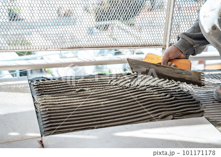 Bricklayer preparing cement on a slab using a notched trowel. I work in a construction. 101171178