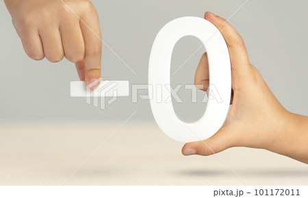 Minus zero. Numeral zero and minus symbol in a hand close-up on a light gray background. The concept of removal or taking away. 101172011