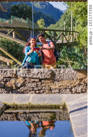 Eco friendly ancient lavoir washhouse. Mixed race mid couple photographing with smartphone. Eco friendly ancient lavoir washhouse. Mixed race mid couple photographing with smartphone. 101173388