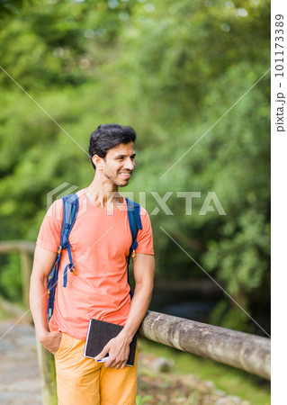 south asian 40s male hiking with a backpack in Asturias green countryside with a diary in spain. south asian 40s male hiking with a backpack in Asturias green countryside with a diary in spain. 101173389