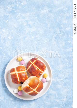 Hot cross buns on white plate with chocolate candy eggs. Traditional easter food, vertical, top view 101174271