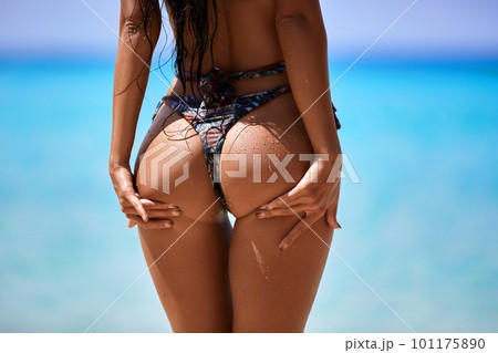 Sexy model's ass in bikini on the blue water background Sexy model's ass in bikini on the blue water background 101175890