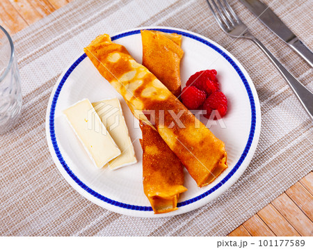 Portion of rolled pancakes with raspberries, honey and pieces of cheese 101177589