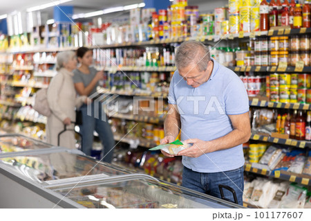 Mature man shopping in supermarket, choosing frozen convenience food Mature man shopping in supermarket, choosing frozen convenience food 101177607