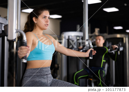 Young girl performing chest exercises in butterfly machine 101177873