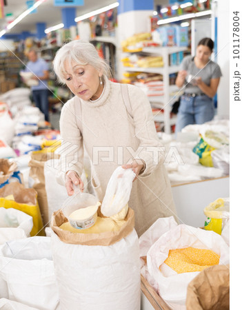 Old woman purchaser buying sugar sand in big supermarket 101178004