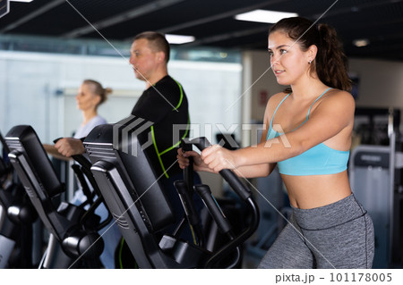 Sporty young woman using elliptical machine in gym 101178005