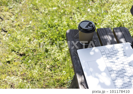 ノートパソコンとベンチと木漏れ日。外でテレワークするイメージ 101178410