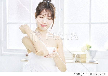 リビングで肘のスキンケアをする女性 101178734