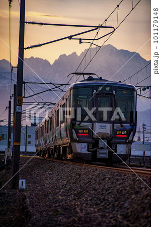 立山連峰剱岳を背景に走る早朝のあいの風とやま鉄道の電車 101179148