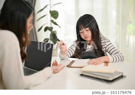 An adorable little Asian girl focuses on studying while her private tutor is teaching English 101179476