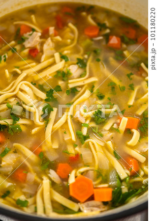 Serving chicken noodle soup with kluski noodles in white ceramic soup bowls. Serving chicken noodle soup with kluski noodles in white ceramic soup bowls. 101180220