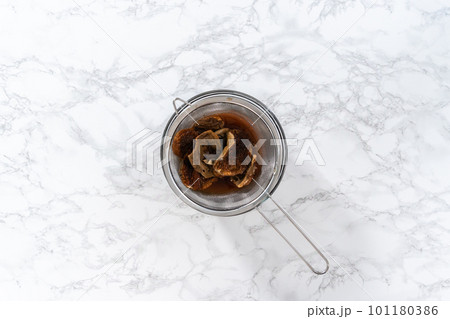 Flat lay. Soaking dehydrated wild mushrooms in a glass mixing bowl with hot water. Flat lay. Soaking dehydrated wild mushrooms in a glass mixing bowl with hot water. 101180386
