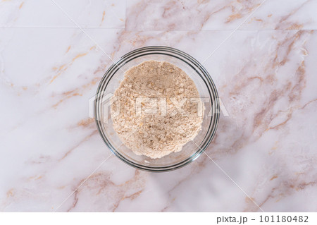 Flat lay. Mixing ingredients in a large glass mixing bowl to bake apple oatmeal cookies. 101180482