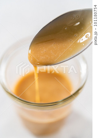 Spooning eggnog caramel sauce from the glass jar. Spooning eggnog caramel sauce from the glass jar. 101180754