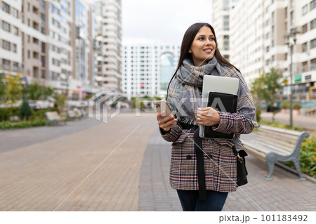 young woman freelancer walking on a walking street with a phone 101183492
