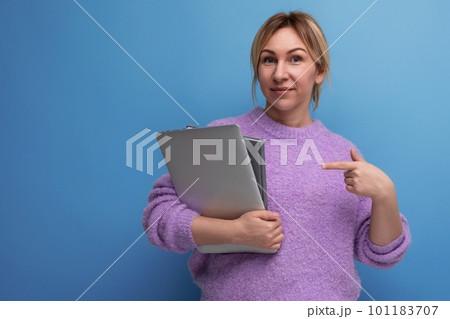 attractive blond woman holding a laptop to study for advertising on a blue background attractive blond woman holding a laptop to study for advertising on a blue background 101183707