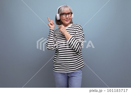 stylish old lady listens to music in headphones on a bright background with copy space 101183717