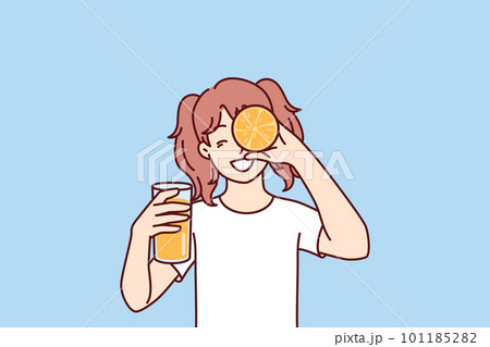 Little girl with glass of orange juice in hands smiling holding half of citrus fruit near face 101185282
