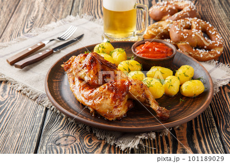 Grilled half chicken with boiled potatoes and tomato sauce served with beer and pretzel closeup. Horizontal 101189029