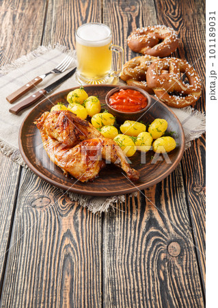 Bavarian roast chicken Hendl with boiled potatoes served with beer and pretzel closeup. Vertical Bavarian roast chicken Hendl with boiled potatoes served with beer and pretzel closeup. Vertical 101189031