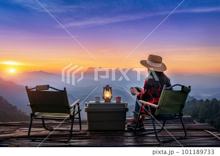Woman taking photos with camera while camping at sunrise. Doi Luang Chiang Dao mountains in Chiang Mai. 101189733