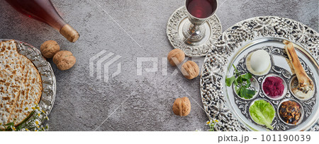 Passover Seder plate with traditional food, walnuts, matza and wine on grunge background 101190039