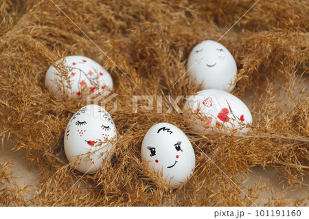 Easter card. Hand made Easter eggs lie in dry natural pampas grass. Painted gentle faces and red hearts. Dry golden reed. Soft selective focus. Happy holidays. Minimalist style. Copy Space 101191160