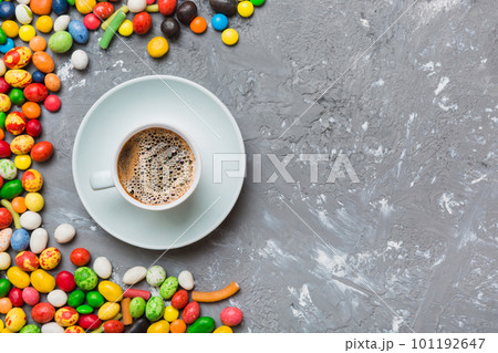 Coffee cup with chocolates and colored candy. Top view on table background with copy space Coffee cup with chocolates and colored candy. Top view on table background with copy space 101192647