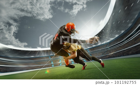 Dynamic image of two men, professional american football players in motion during game at open air 3D stadium at daytime with blurred stands 101192755