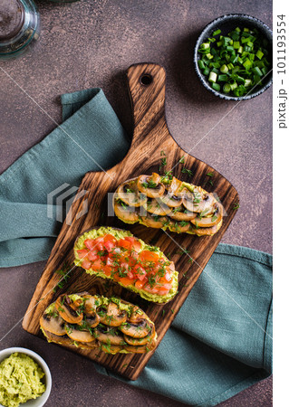 Sandwiches on rye bread with guacamole, fried mushrooms, tomatoes and dill top and vertical view 101193554