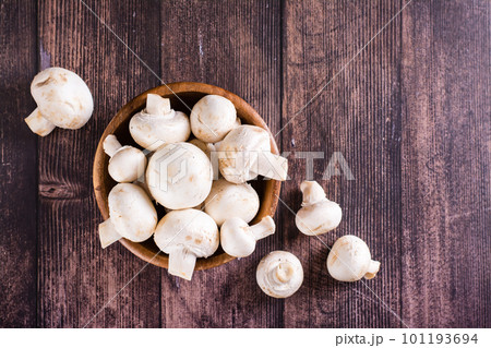 Raw whole champignons in a bowl and on a wooden table top view Raw whole champignons in a bowl and on a wooden table top view 101193694