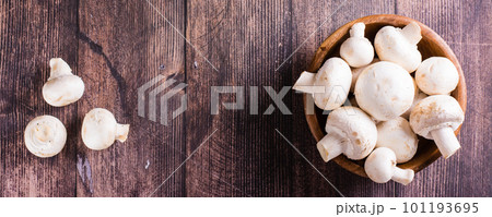 Whole fresh champignons in a plate and on a wooden table top view web banner 101193695