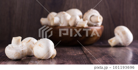 Close-up whole fresh champignons on a wooden table and in a bowl on the background web banner Close-up whole fresh champignons on a wooden table and in a bowl on the background web banner 101193696