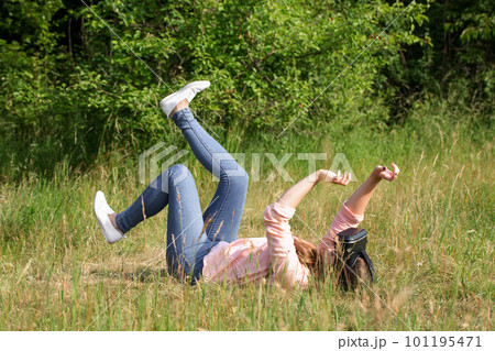Young woman wearing virtual reality glasses lying on a meadow in the park Young woman wearing virtual reality glasses lying on a meadow in the park 101195471