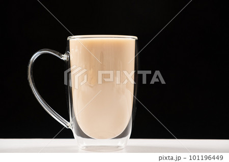 Tea with milk in a glass cup with a double bottom on a white and black background Tea with milk in a glass cup with a double bottom on a white and black background 101196449