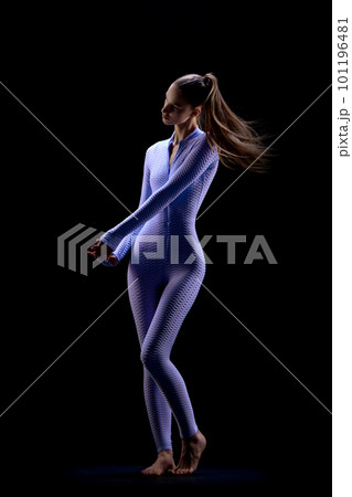 Shot of adorable young woman with long hair wearing suit and posing over dark background. Female body in motion Shot of adorable young woman with long hair wearing suit and posing over dark background. Female body in motion 101196481