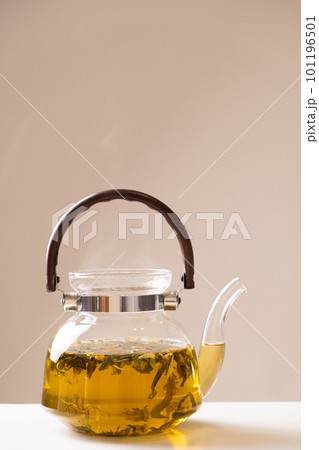 Green Chinese tea with orange zest in a glass teapot on a beige background Green Chinese tea with orange zest in a glass teapot on a beige background 101196501