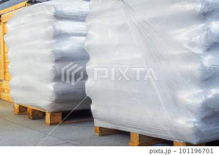 Storage of packaged goods or cargo in warehouse. On wooden pallets there are bags of cement wrapped Storage of packaged goods or cargo in warehouse. On wooden pallets there are bags of cement wrapped 101196701