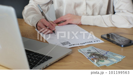 Close up woman filling tax return form. Female calculating expenses and writing on tax document. Close up woman filling tax return form. Female calculating expenses and writing on tax document. 101199563