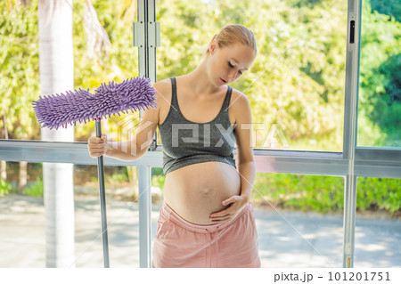 Pregnant woman washes the floor and is tired. Tired pregnant woman having pain in back while she is cleaning her house 101201751