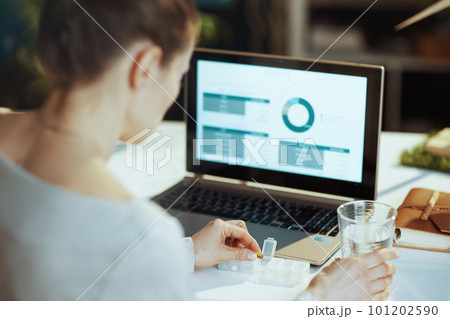 Seen from behind modern woman with laptop and pills 101202590