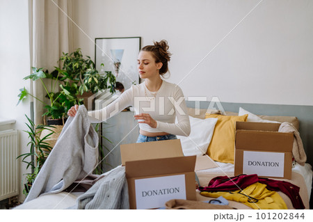 Young woman giving her clothes to charity. 101202844