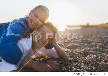 Happy young woman lying on her boyfriends back, looking at camera, having fun together. Happy young woman lying on her boyfriends back, looking at camera, having fun together. 101203064